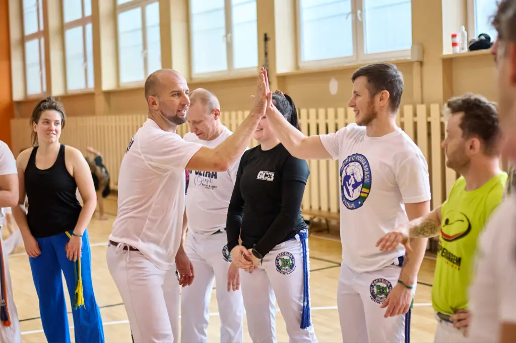 Capoeiriści przybijający piątkę podczas treningu w Academia Capoeira w Łodzi – współpraca zamiast rywalizacji
